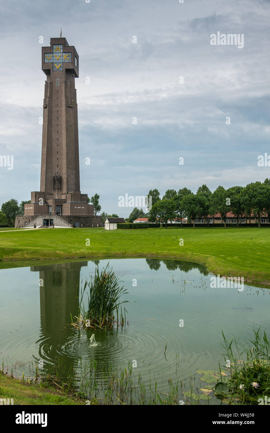 Diksmuide, Flanders, Belgium -  June 19, 2019: IJzertoren, tallest peace monument of WW 1 against gray blue cloudscape. On wall saying No More War. Re Stock Photo