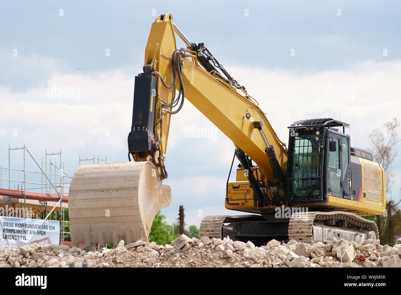 A non-working excavator stands on the rubble heap of a construction site. Stock Photo