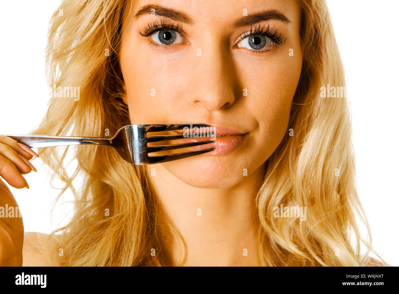 Young woman pressing fork to her lips and looking at camera. Nutrition concept. Stock Photo