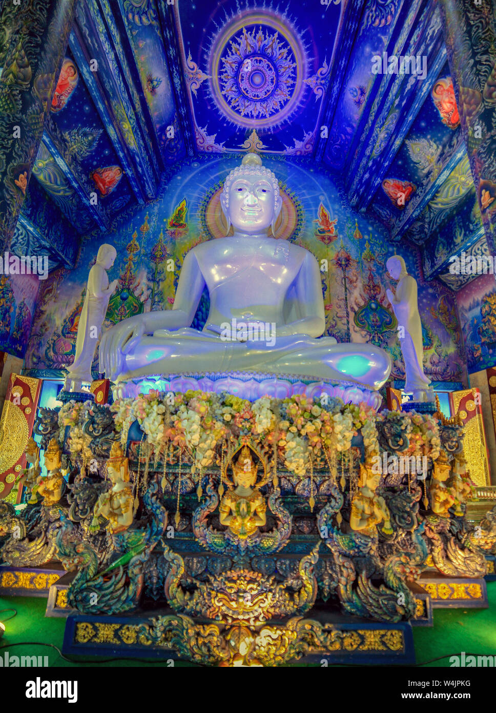 Interior of the Blue Temple, Wat Rong Seua Ten, with a huge pearlescent white statue of Buddha against a richly decorated and mostly blue painted ceil Stock Photo