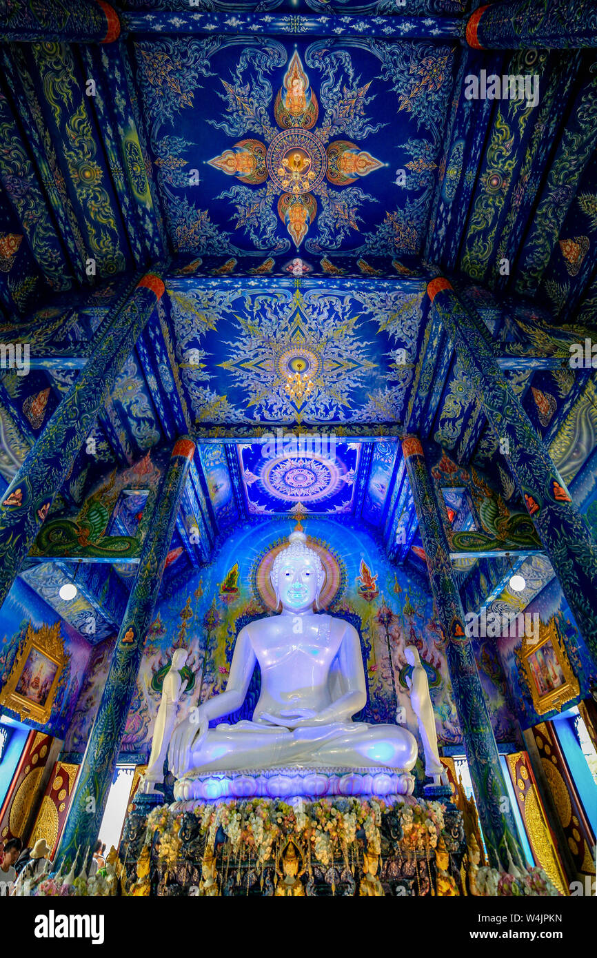 Interior of the Blue Temple, Wat Rong Seua Ten, with a large, white statue of Buddha. Ceilings are painted in blue with rich, intricate Buddhist symbo Stock Photo