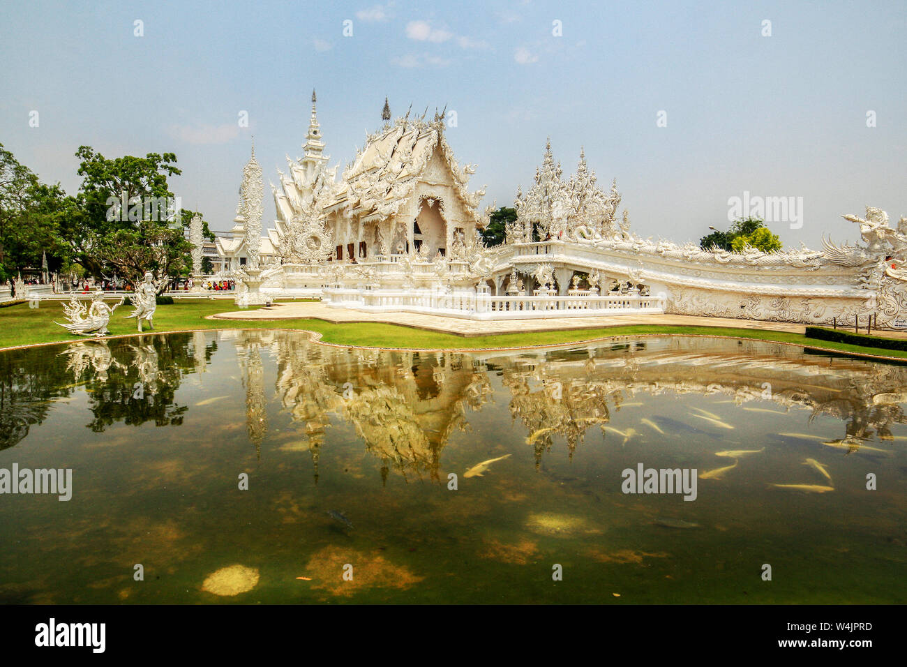 The Bridge symbolizing the Cycle of Rebirth leads to Wat Rong Khun, White Temple, across a Koi pond at Chiang Rai, Thailand. Stock Photo