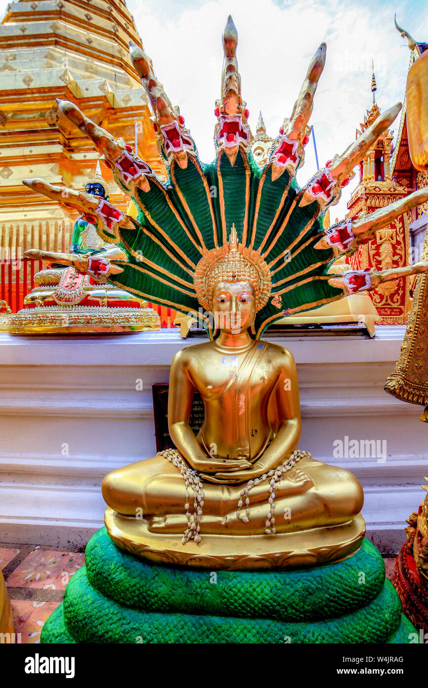 Statue of a golden Buddha with an impressive green and gold halo radiating from his head at Wat Phra That Doi Suthrep in Chiang Mai, Northern Thailand Stock Photo