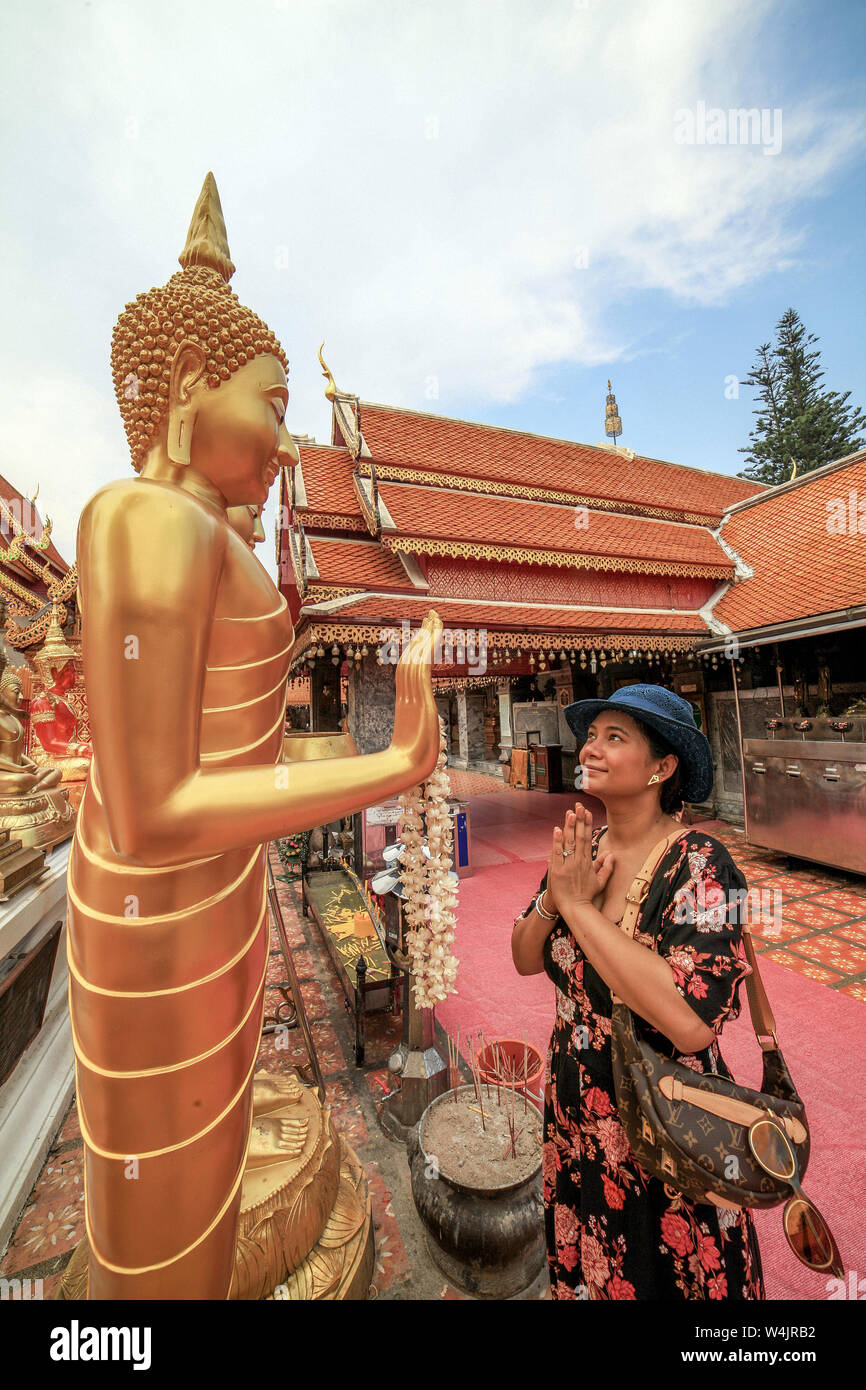A Thai woman tourist prays before a life-size statue of Buddha at the Wat Phra That Doi Suthep in Chaing Mai, Thailand. Stock Photo