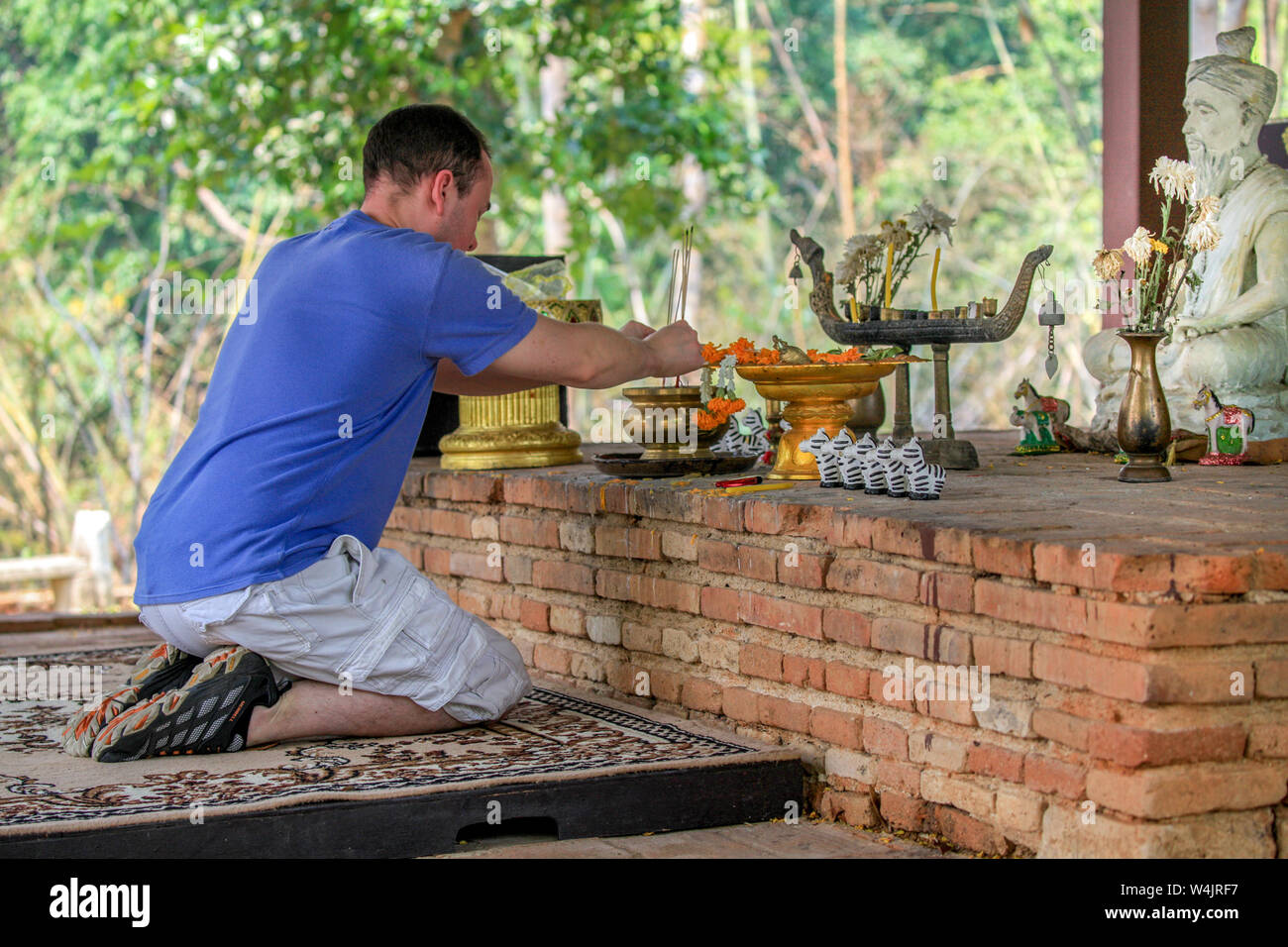 A Caucasian man prays at Wat Ku Din Khao, an 800-year old Buddhist temple on the grounds of the Chiang Mai Zoo, Thailand. Stock Photo