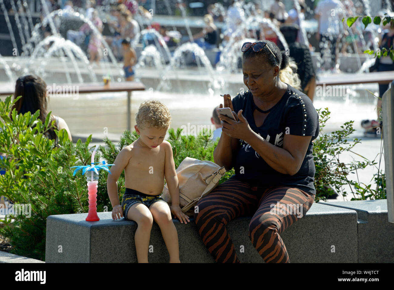 Black lady on phone, with MR child. Stock Photo