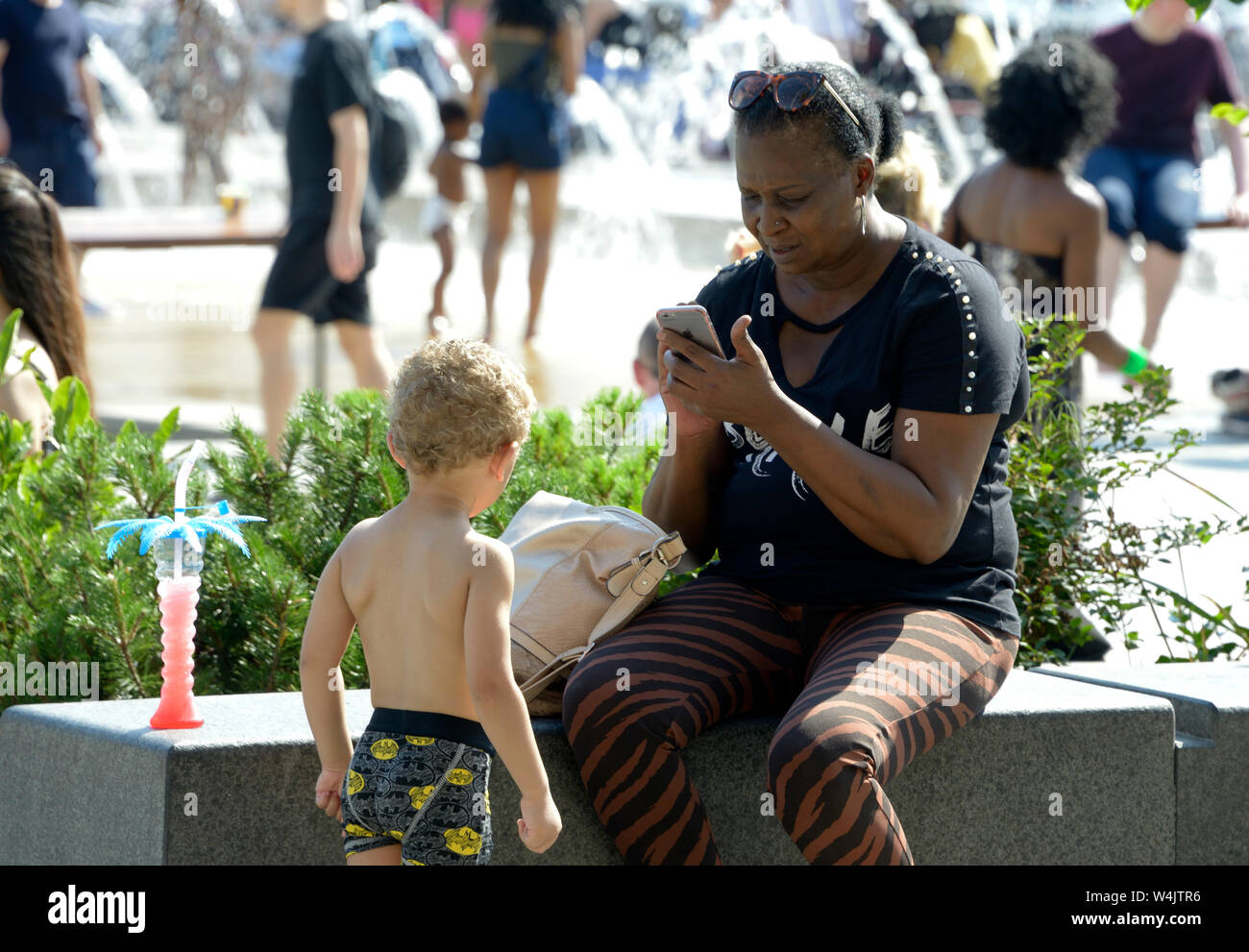 Black lady on phone, with MR child. Stock Photo