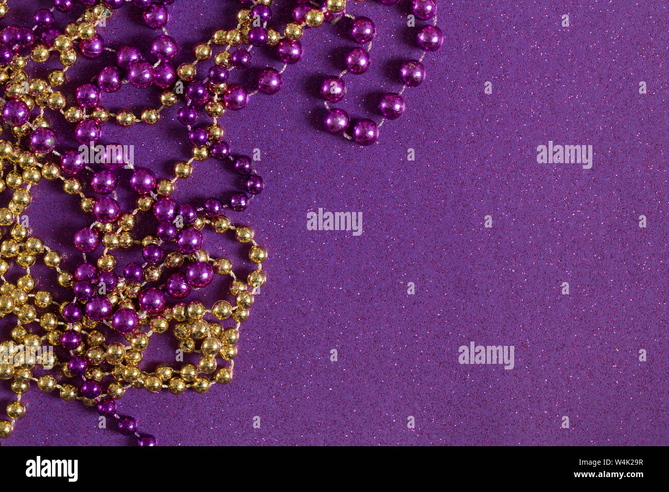 Mardi Gras Beads on a Purple Glitter Background Stock Photo - Alamy