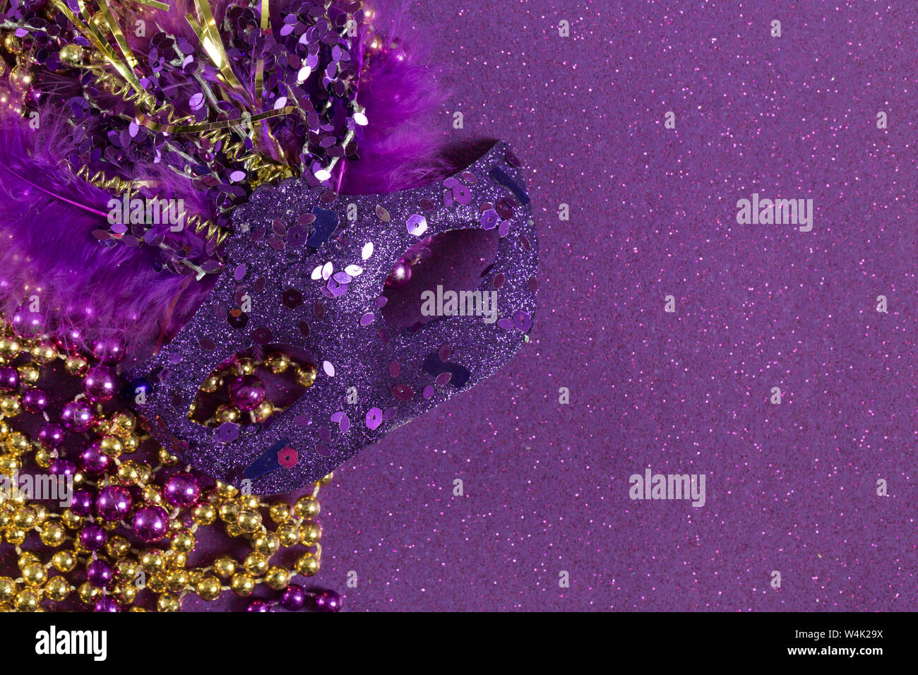 Purple Mardi Gras Mask on a Purple Glitter Background with Beads Stock