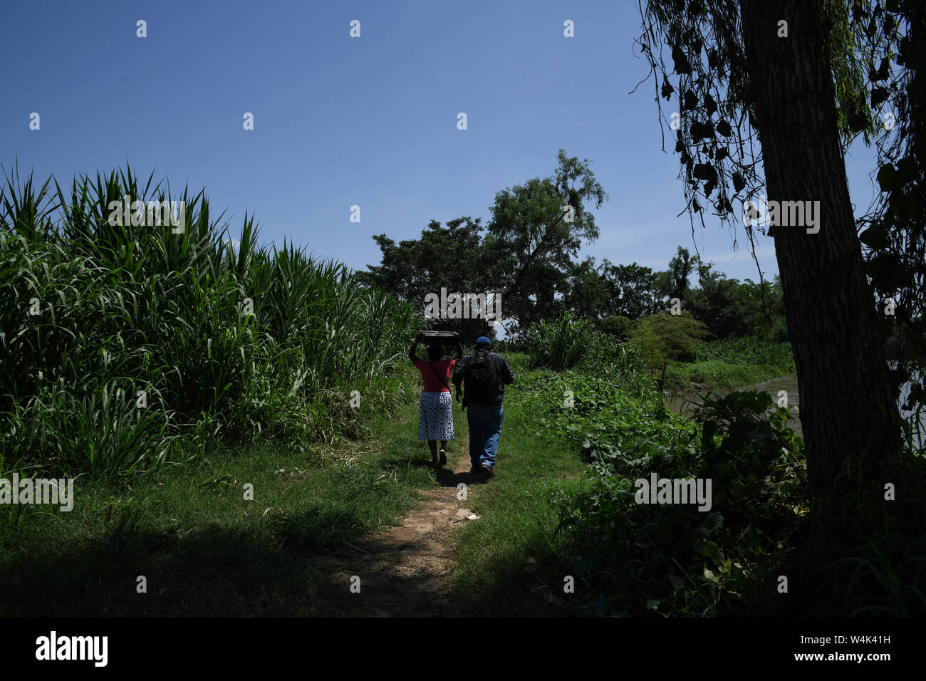 Tapachula, Chiapas, Mexico. 23rd July, 2019. A Honduran couple crosses from Los Limones, Guatemala to Libertad, Mexico on Tuesday. As the US has pressured Mexican authorities to crack down on migrants crossing the country to reach the U.S., such crossings have moved to sleepy areas like Libertad, where there is little or no official Mexican border security. Credit: Miguel Juarez Lugo/ZUMA Wire/Alamy Live News Stock Photo