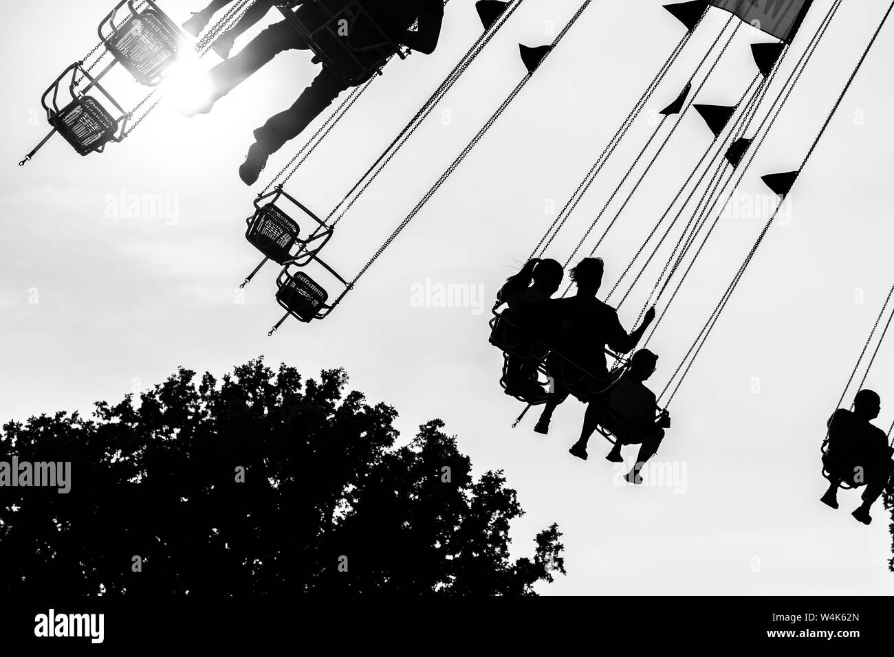 Volksfest Besucher im Ketten Karussell im Gegenlicht Schwarz Weiss Stock Photo