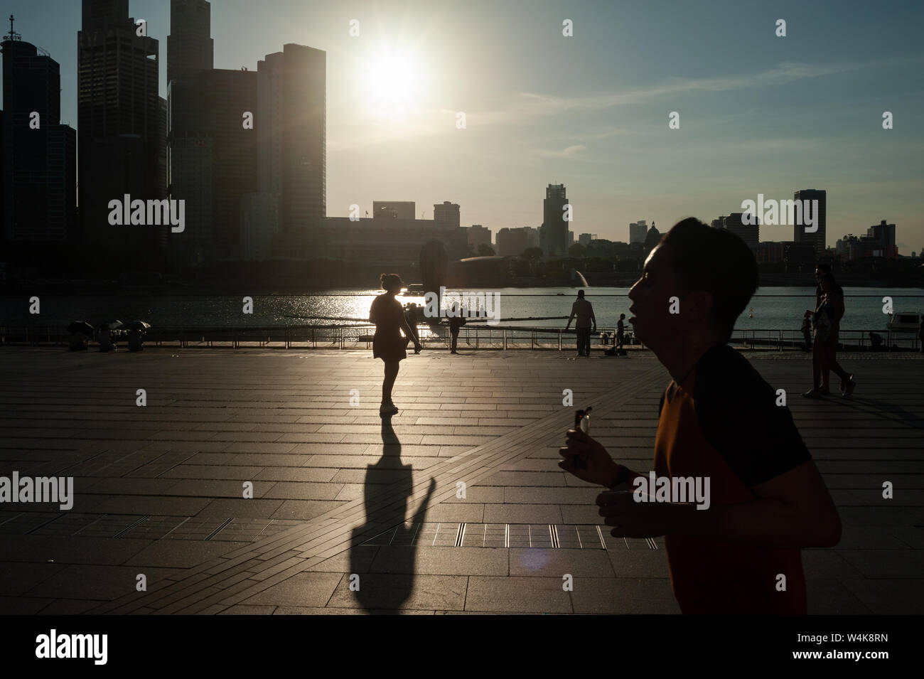 19.07.2019, Singapore, Republic of Singapore, Asia - People at the waterfront in Marina Bay with the city skyline of the central business district. Stock Photo
