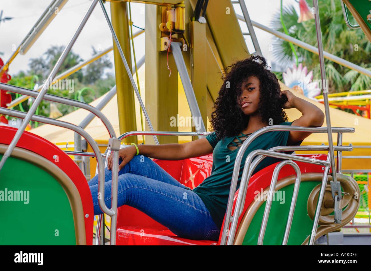 young girl of black color, laughing hair in ferris wheel, sitting enjoying a summer day, lifestyle portrait Stock Photo