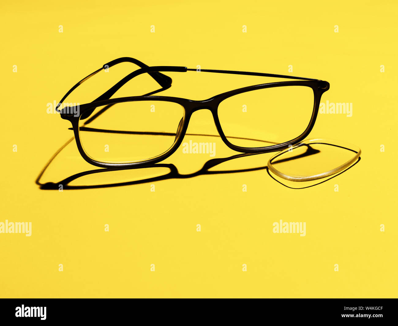 Broken glasses, eyeglasses, lens fallen out on yellow background for copyspace. Optical health or eyewear. Stock Photo