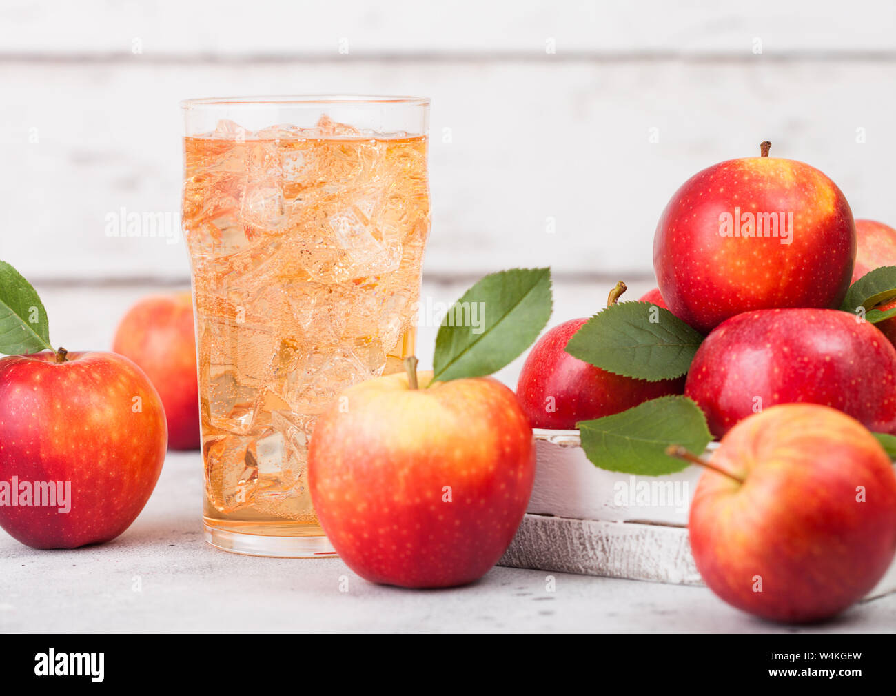 Glass of homemade organic apple cider with fresh apples in box on wooden background, Glass with ice cubes Stock Photo