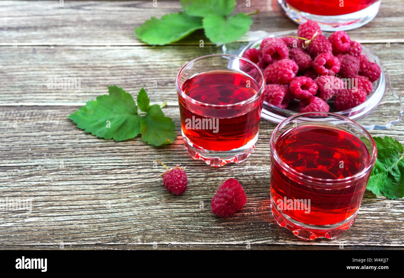 Raspberry liqueur in glass, fresh natural ripe organic berries and