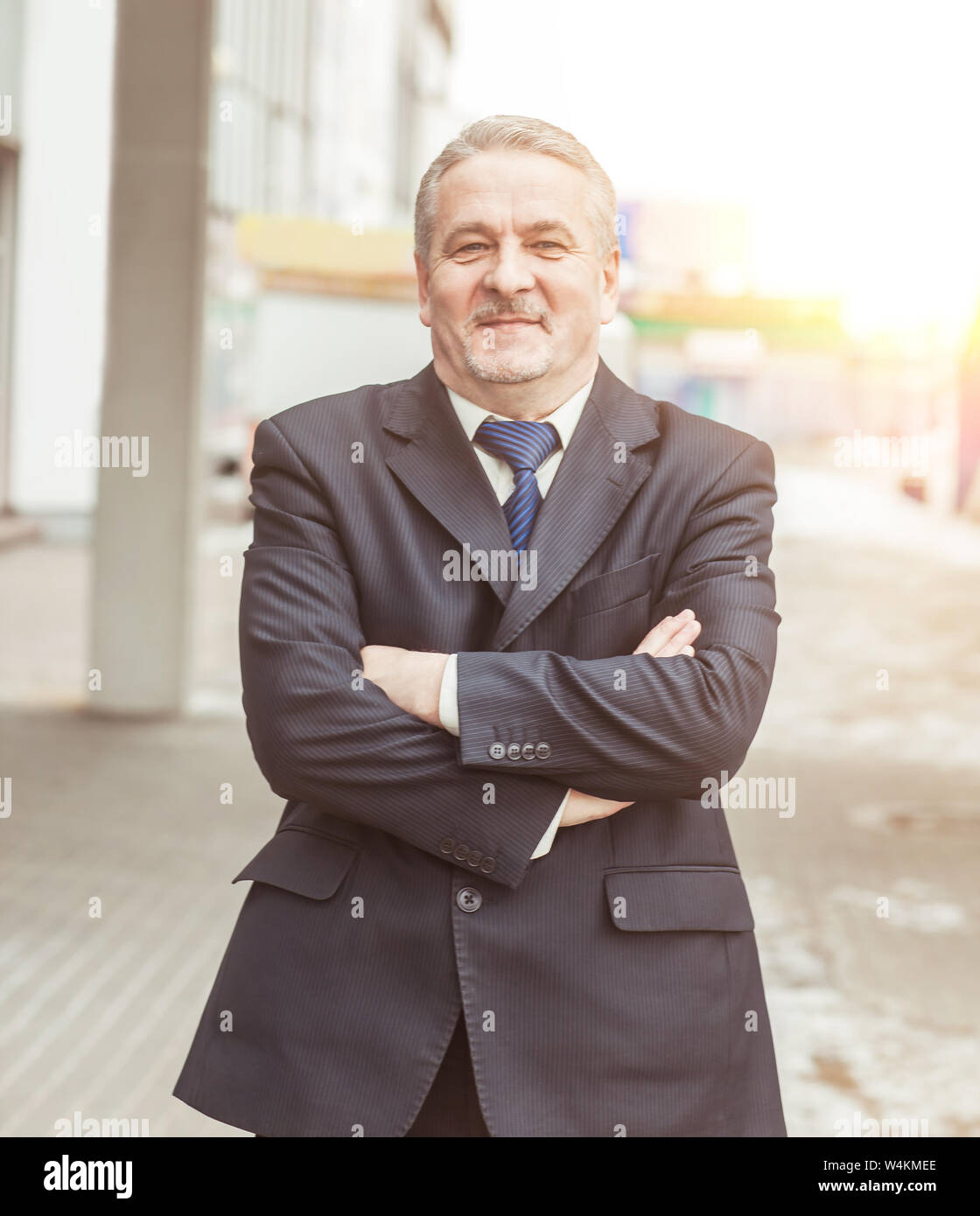 portrait of a successful businessman standing with crossed hands in ...