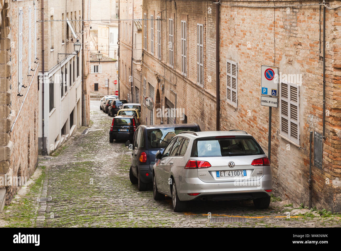 Fermo, Italy - February 11, 2016: Perspective view of narrow street with parked cars in Fermo, Italian old town Stock Photo