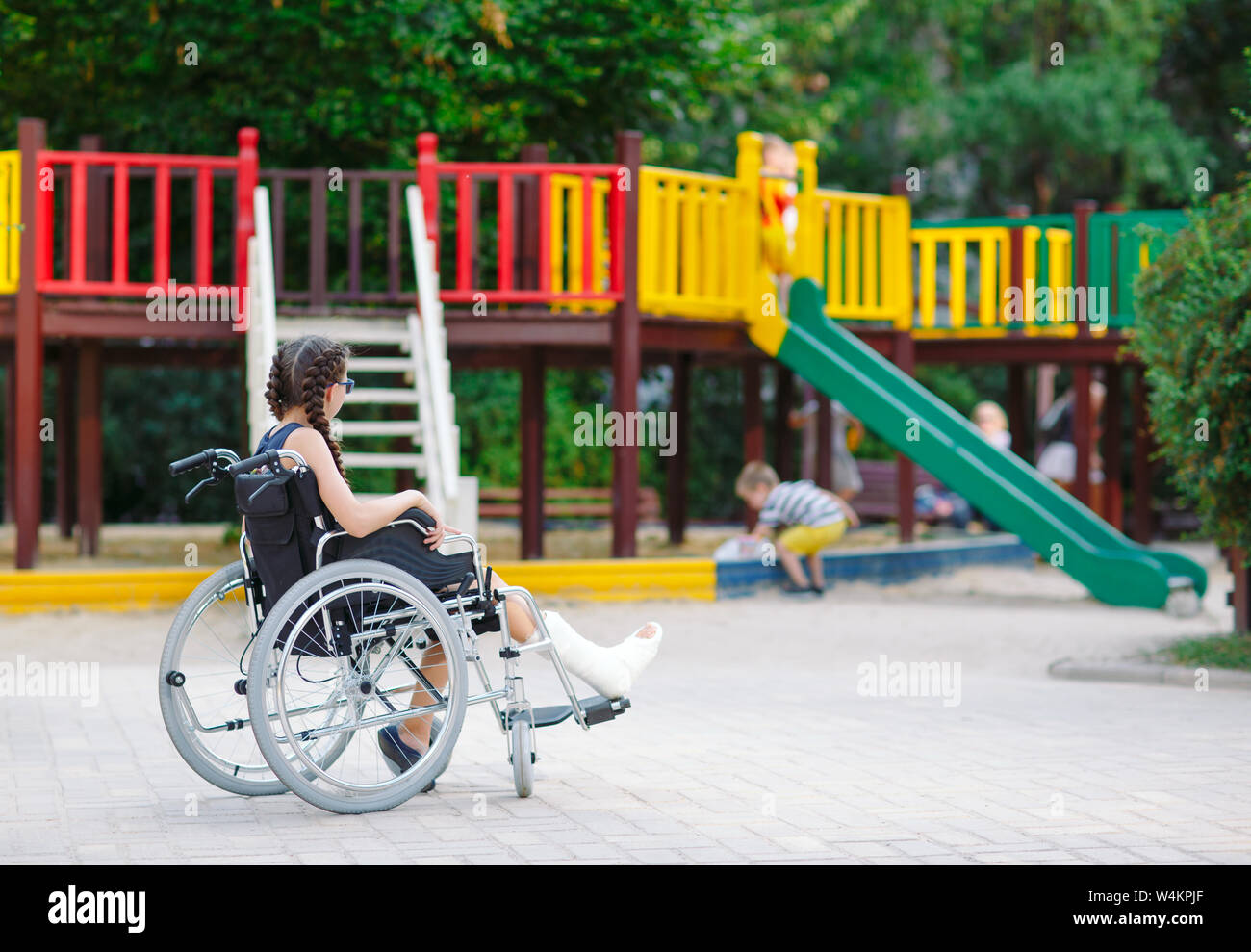 A girl with a broken leg sits in a wheelchair in front of the