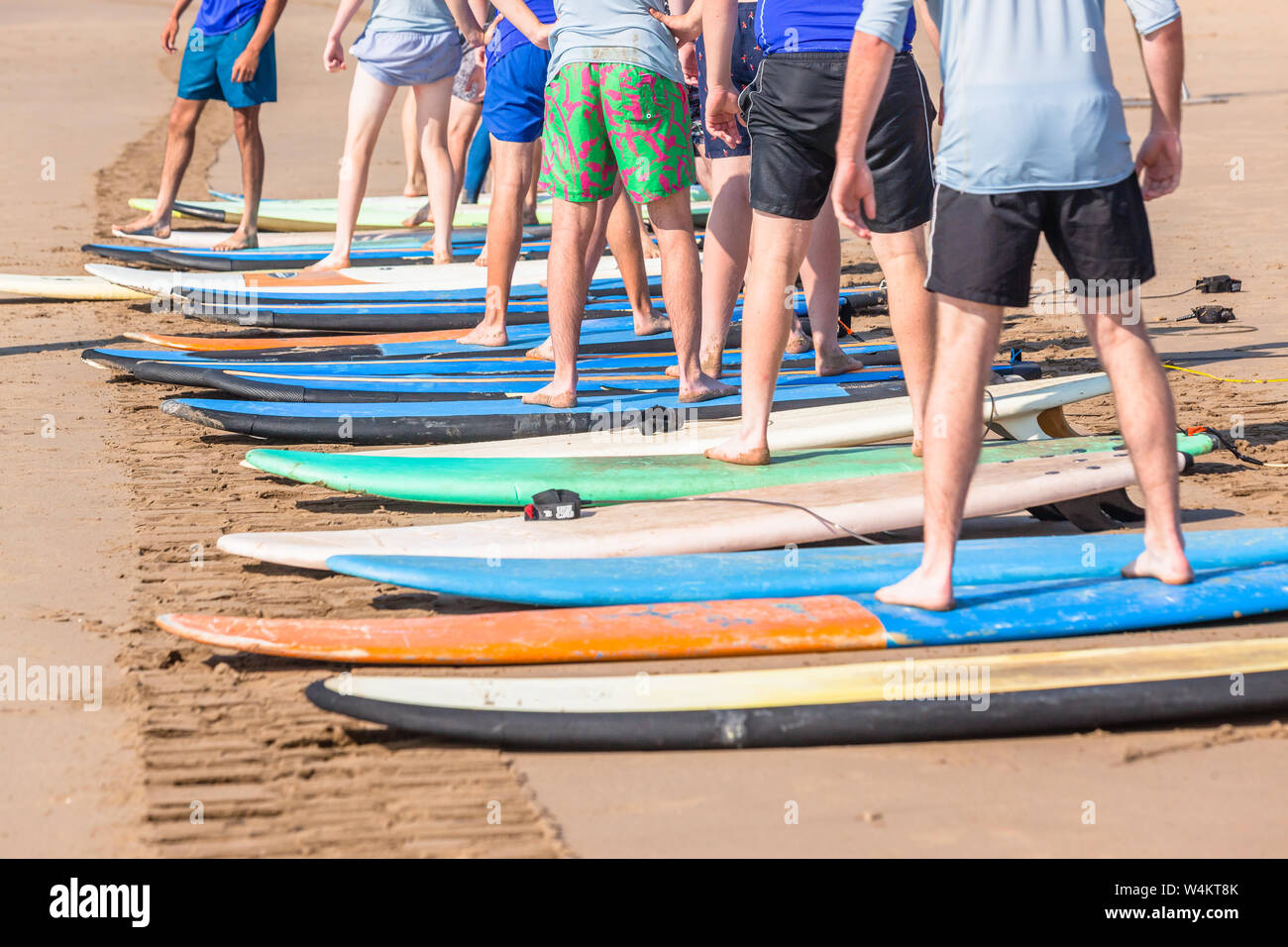 Surfing lessons on beach young men legs standing on surfboards basic