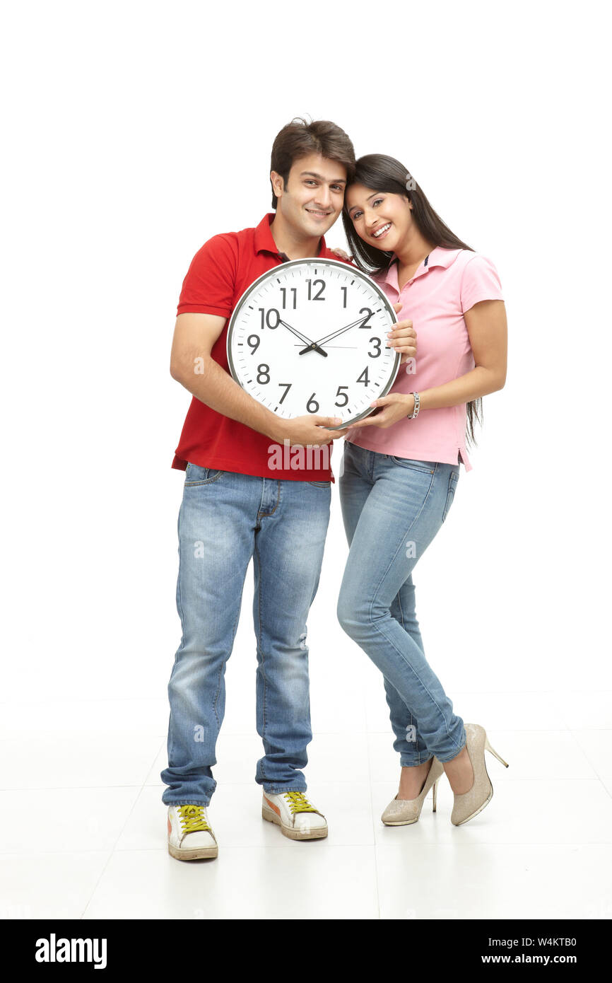Couple holding clock and smiling Stock Photo - Alamy