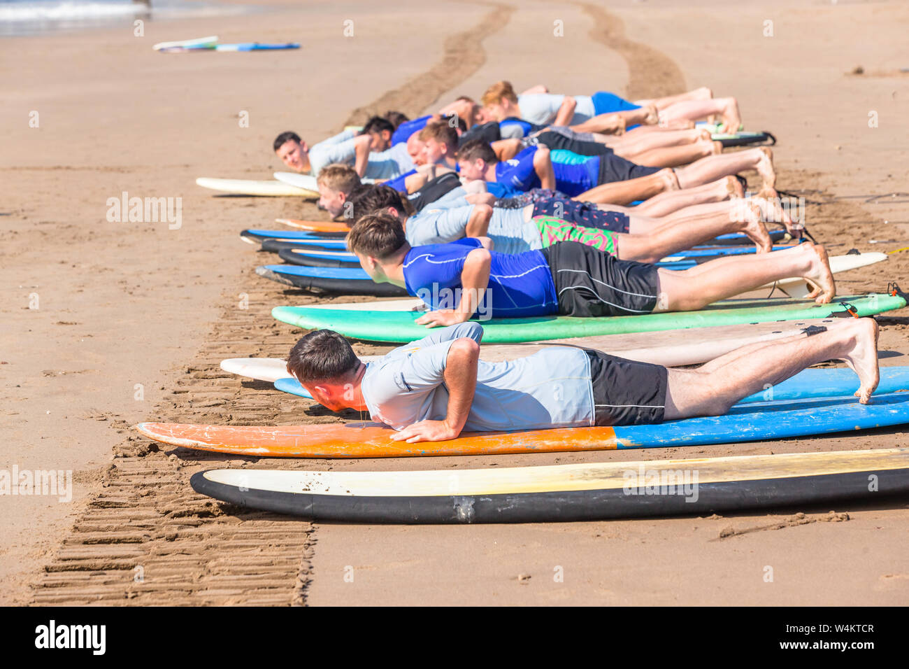 Surfing lessons on beach with surfboards with young men and surfer