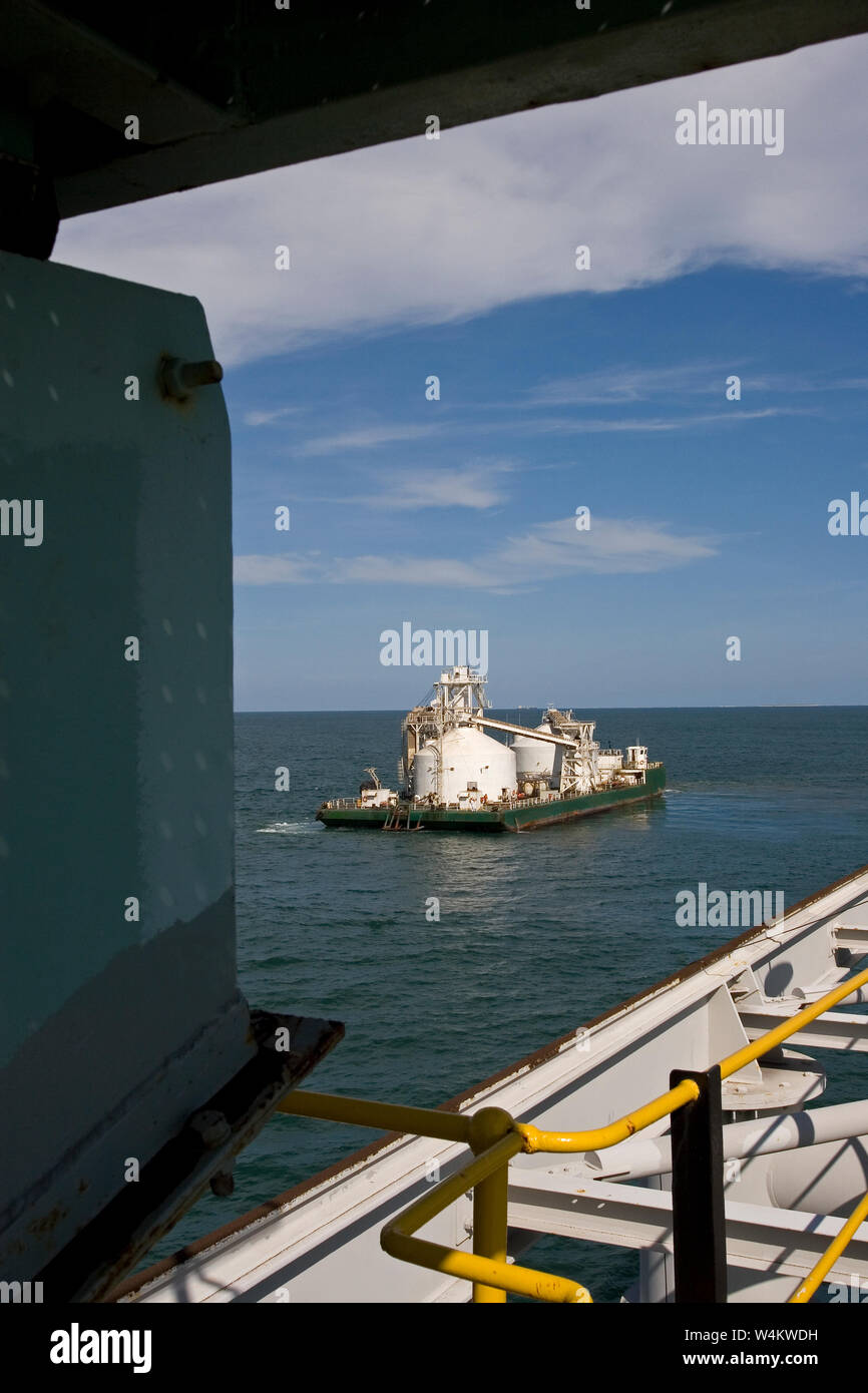 Mining, managing & transporting of titanium mineral sands. Custom built barge arriving back at port jetty after discharging product into OGV at sea. Stock Photo