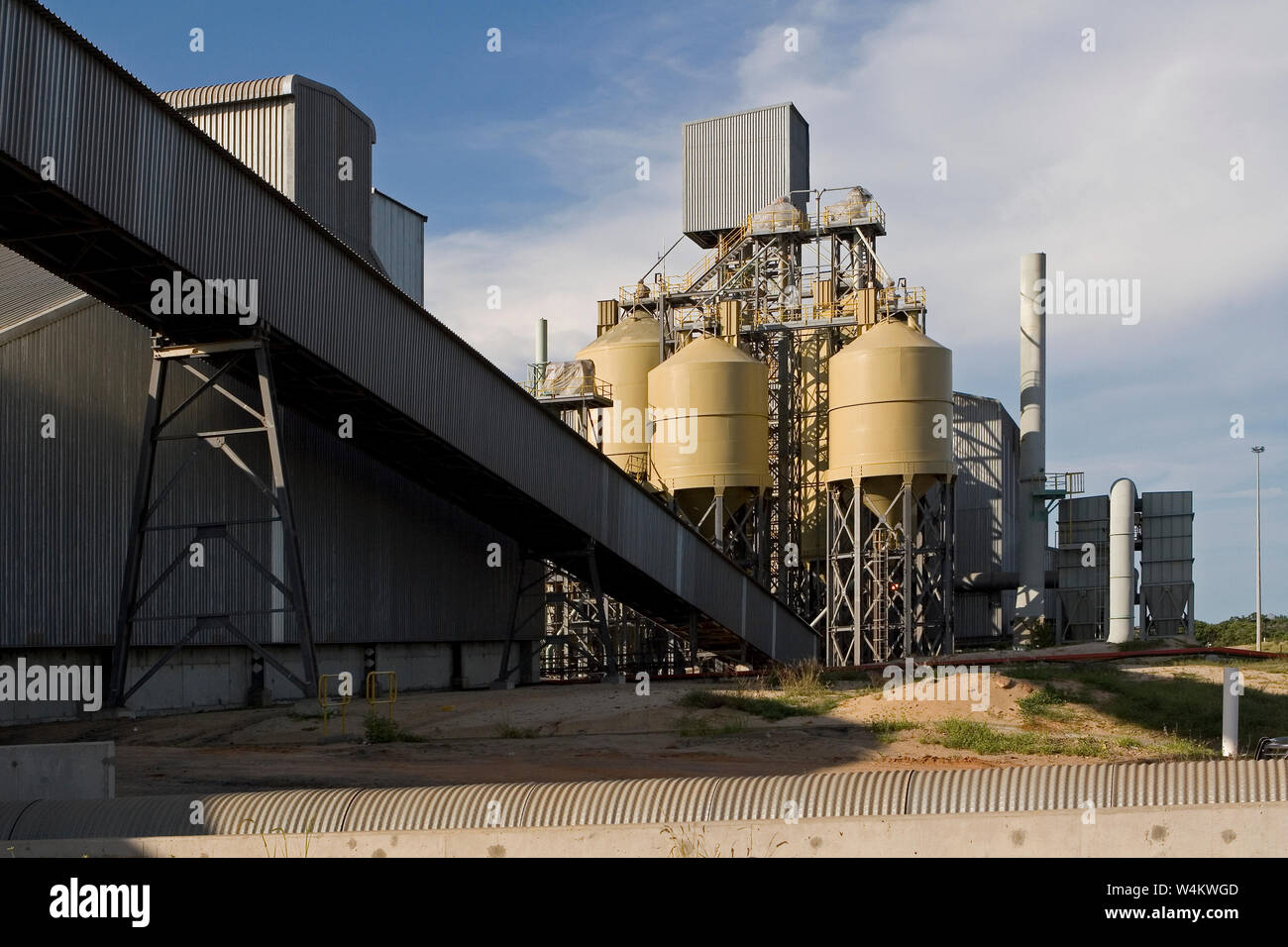 Mining, managing & transport of titanium mineral sands. Rear of warehouse & storage silos containing mineral products plus start of conveyor to port. Stock Photo