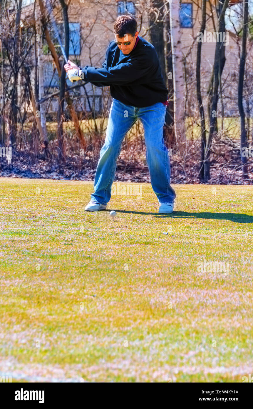 A golfer swinging for the golf ball from the teeing box. Stock Photo