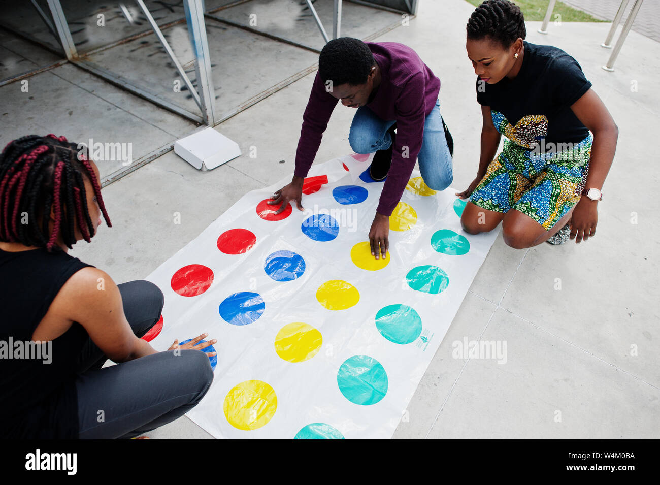 Group of three african american friends play twister game outdoor. Stock Photo