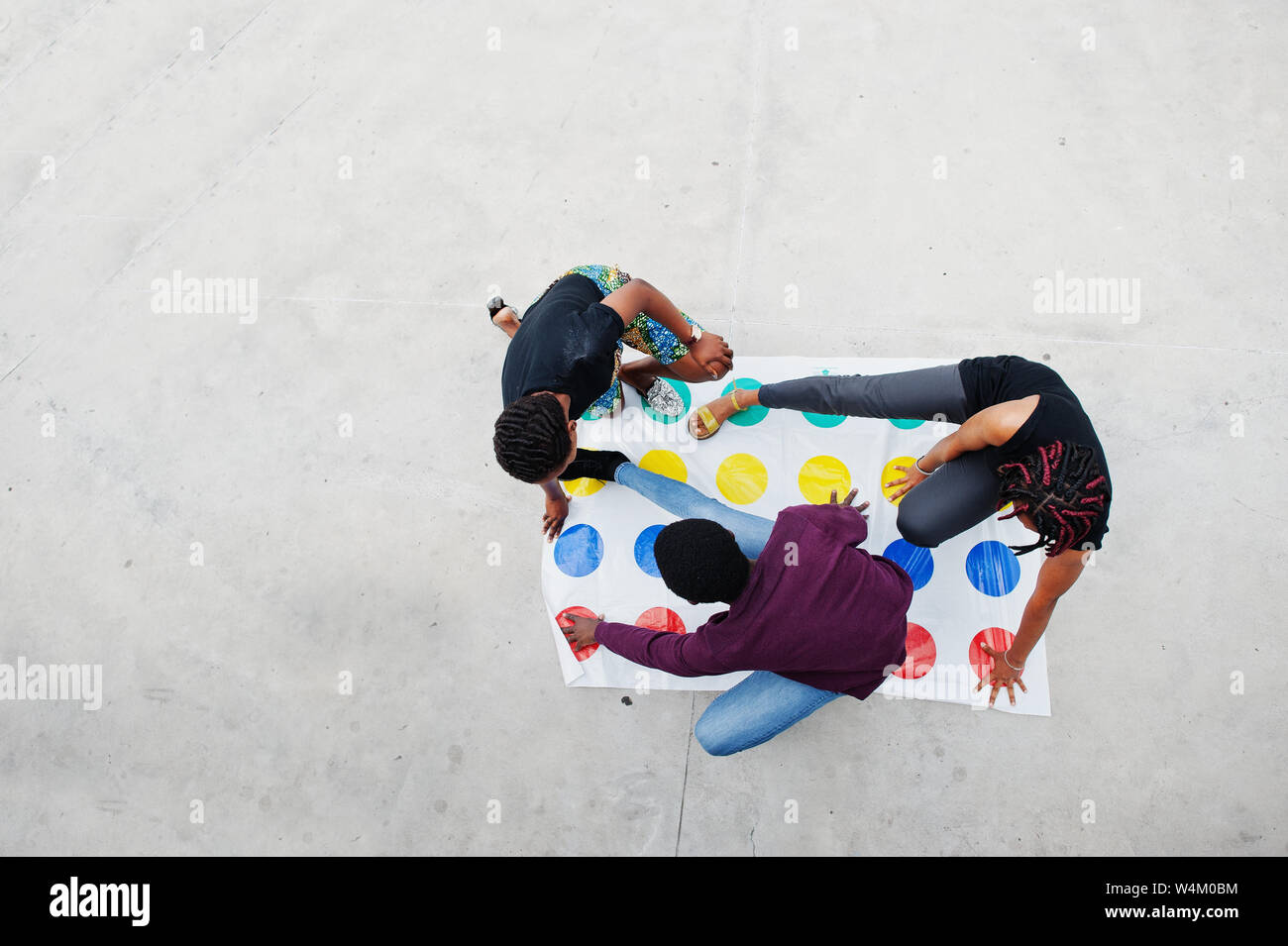 Group of three african american friends play twister game outdoor. Stock Photo