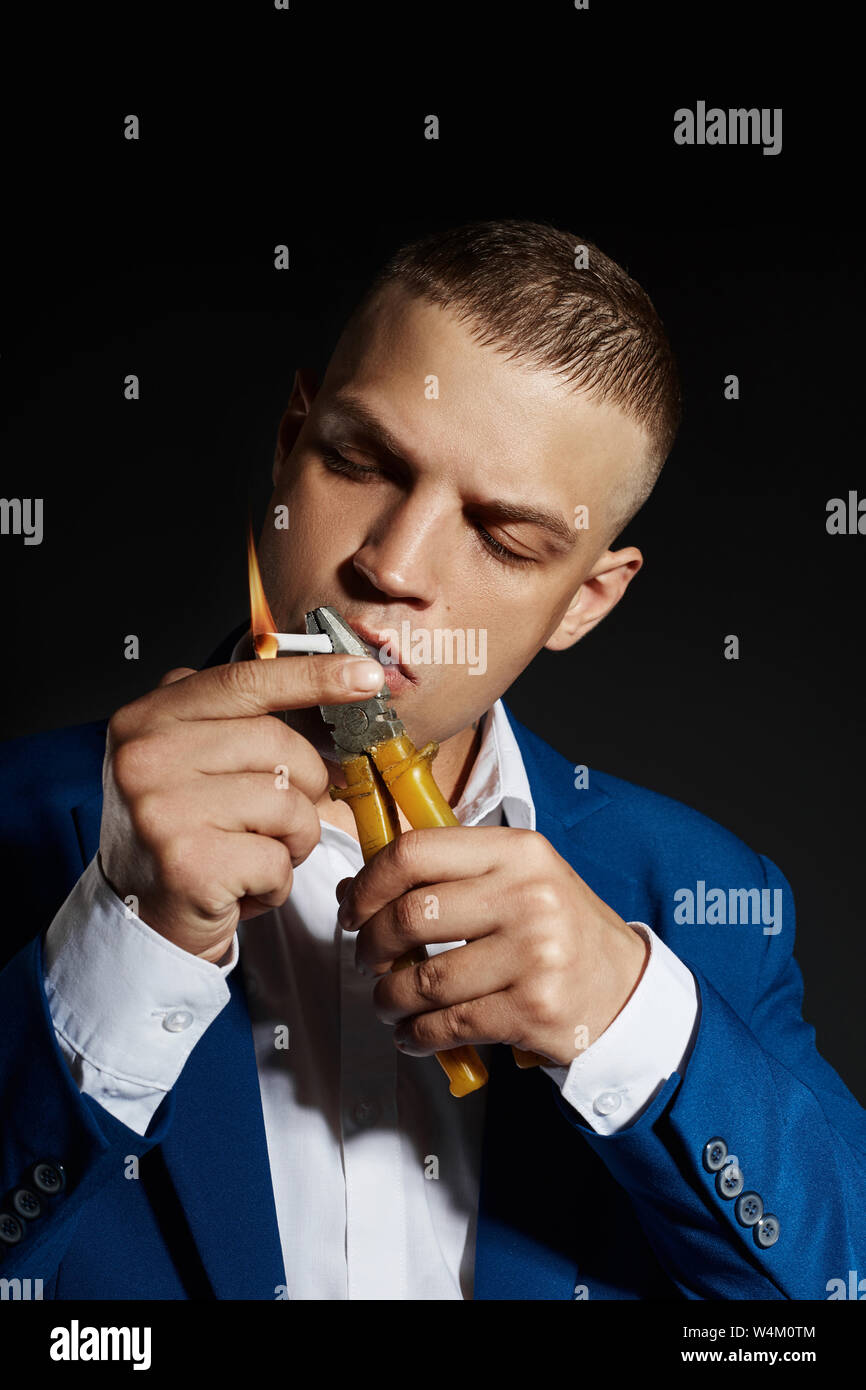 Contrast portrait of a Smoking man businessman in an expensive business suit on a dark background. Successful emotional Manager businessman posing ges Stock Photo