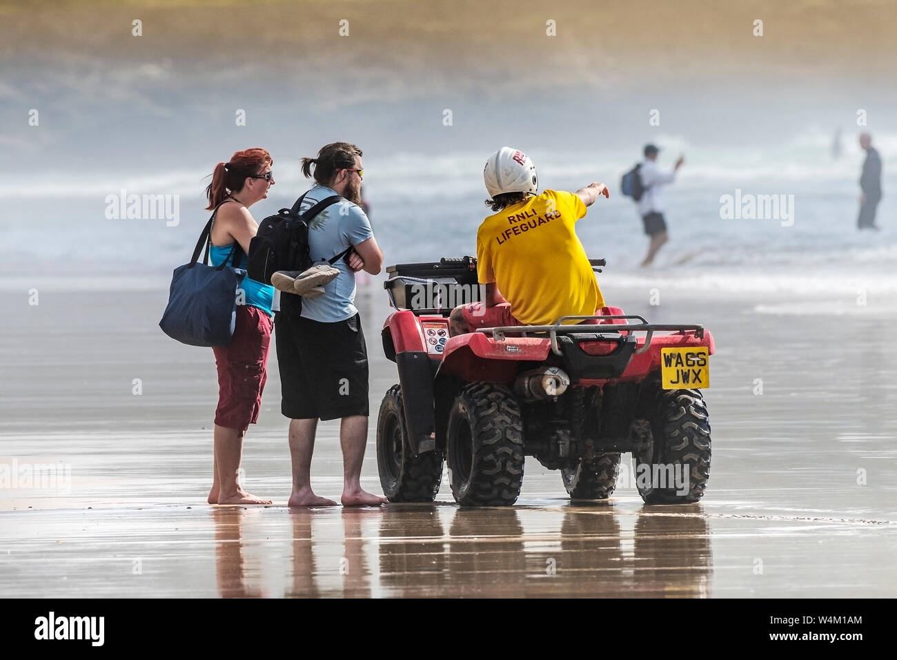 A RNLI Lifeguard advising holidaymakers to the safe bathing areas at Fistral Beach in Newquay in Cornwall. Stock Photo