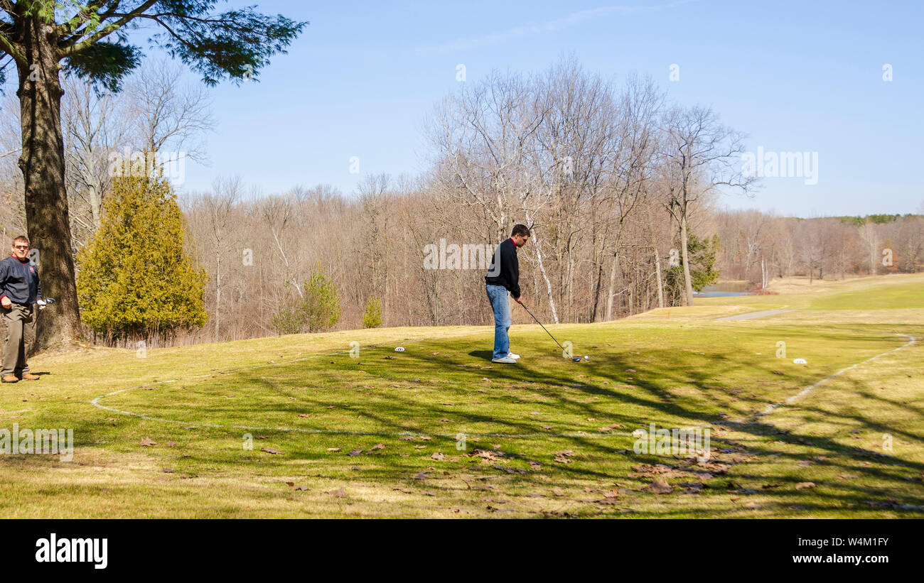 A teeing ground on a golf course. A couple of golfers are seen preparing to tee off from the first hole of a golf course. Stock Photo