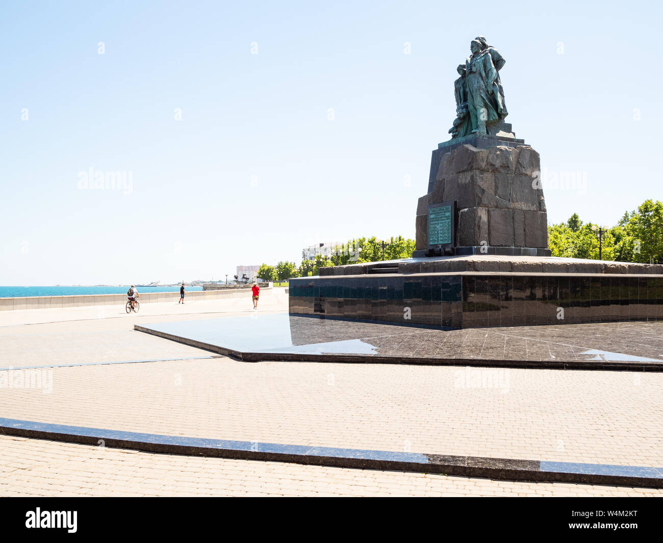 NOVOROSSIYSK, RUSSIA - JULY 7, 2019: people walk on Admiral Serebryakov Embankment and Monument to the Dead Fishermen of Seiner Urup on Cape of Love i Stock Photo