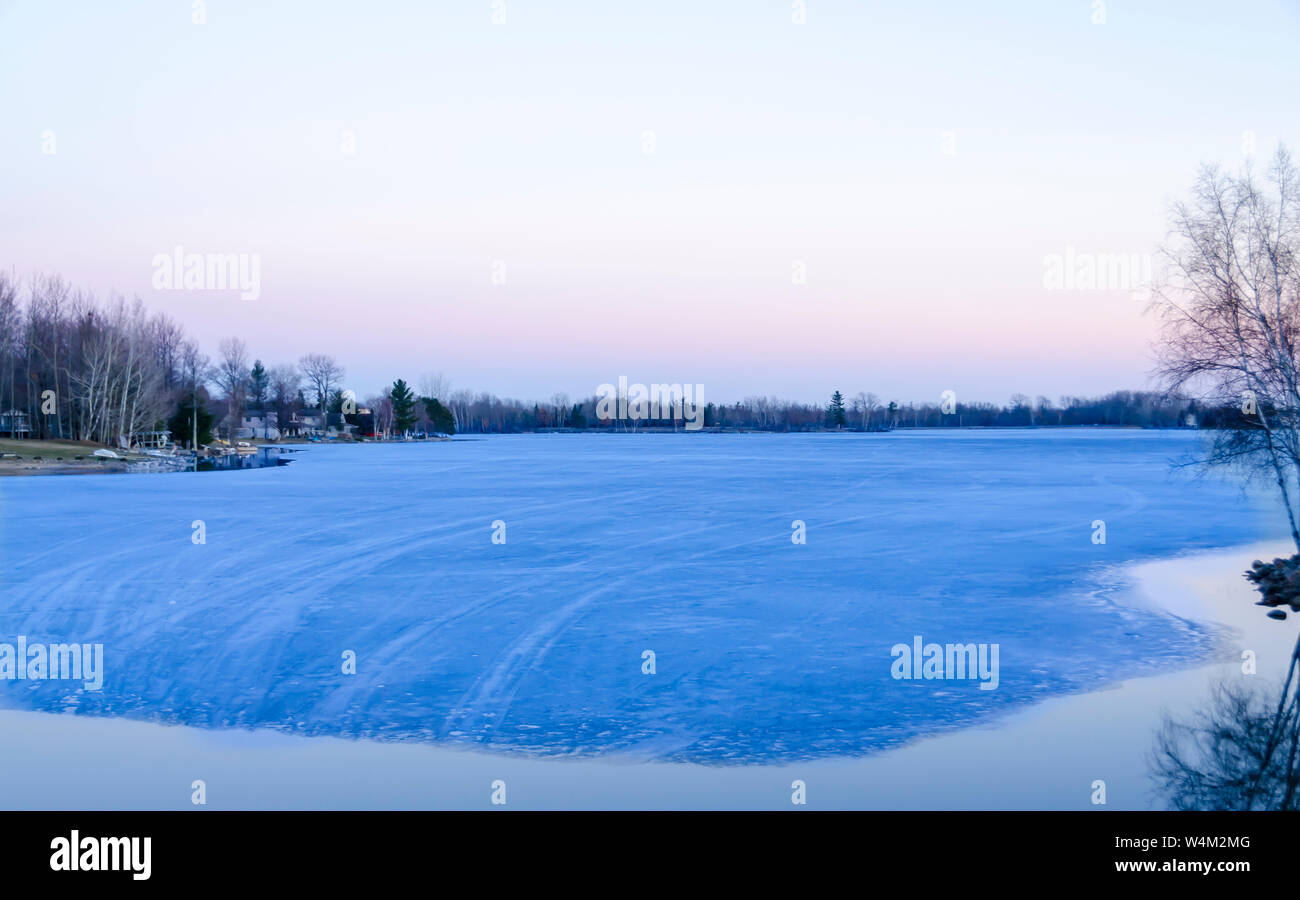 Houses next to a thawing lake. Upper Michigan, USA. Stock Photo