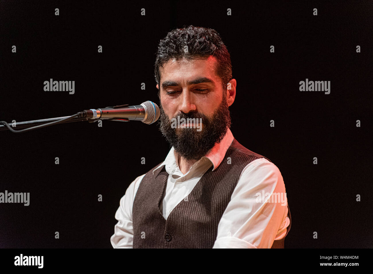 Good-looking man with thick black beard, musician plays on stage Stock Photo