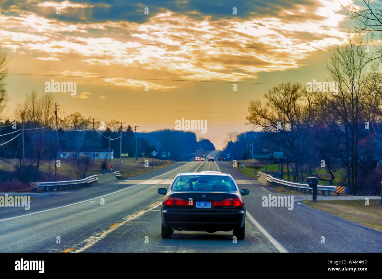 Cars plying on a Northern Michigan freeway, USA, under a colorful evening sky. Stock Photo