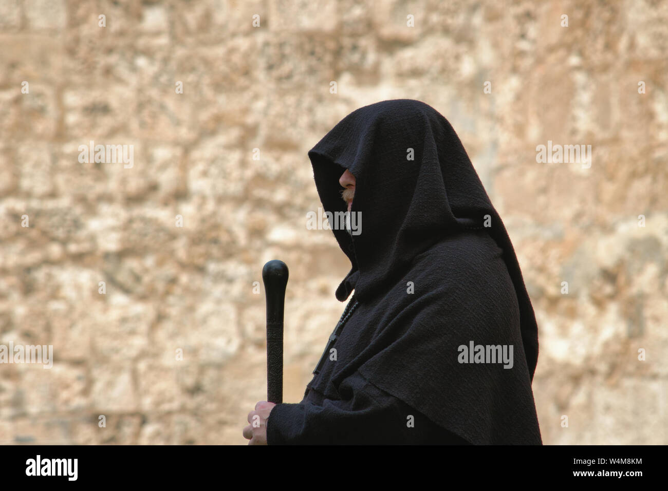 Hooded spooky looking medieval monk in a traditional black robe with staff Stock Photo