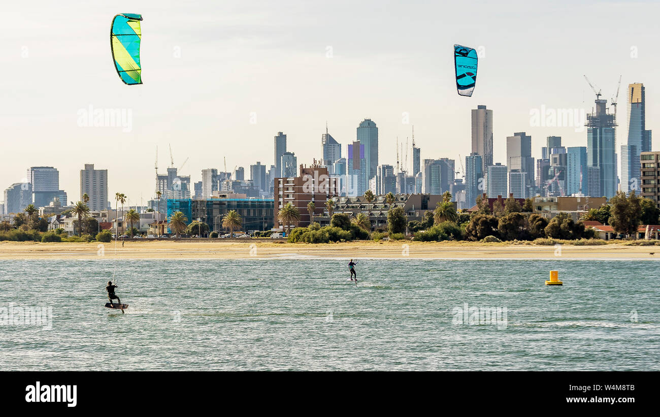 Pair of kitesurfers trains in Port Phillip Bay, with the skyline of