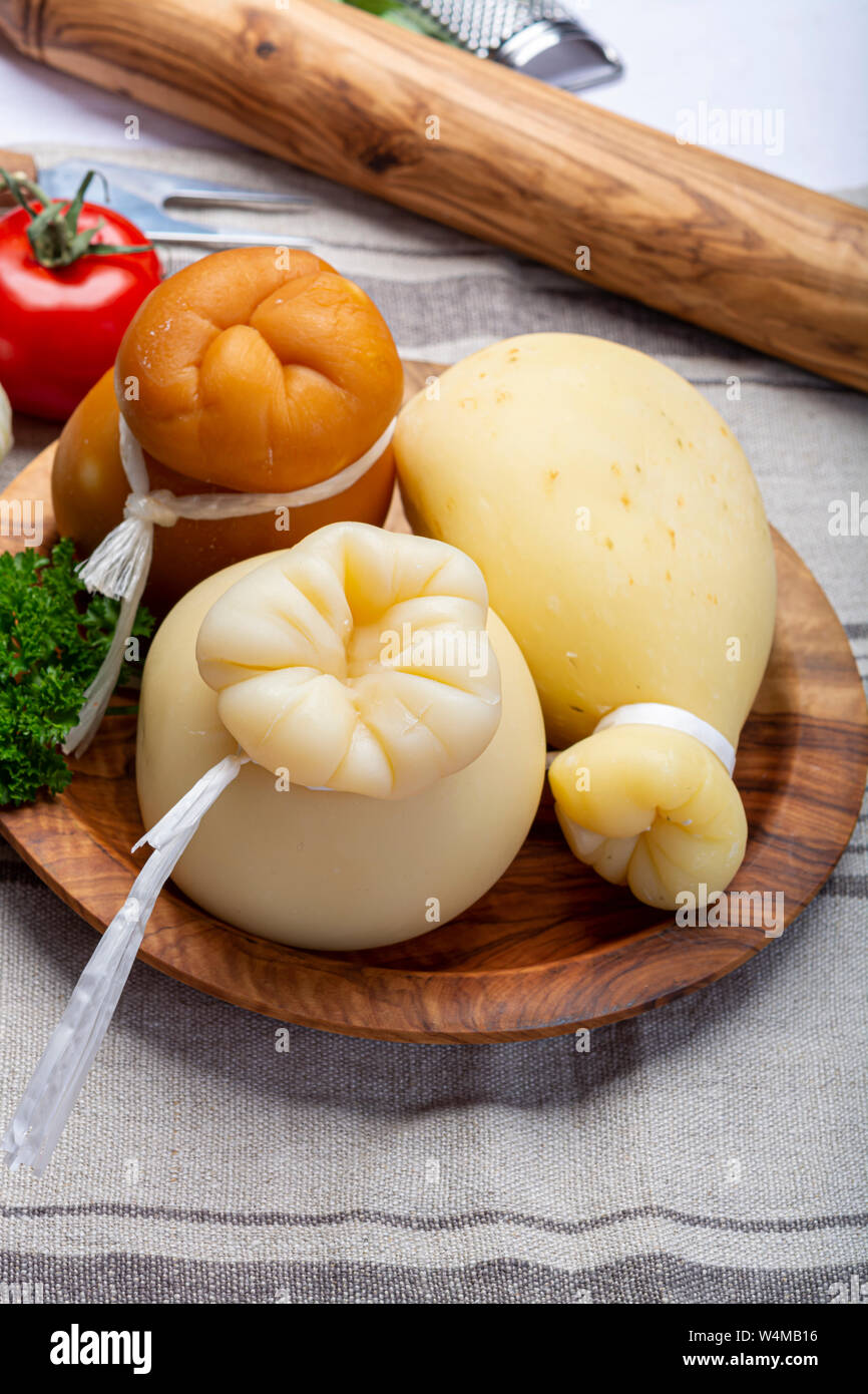 Cheese collection, Italian provolone or provola caciocavallo hard and smoked cheeses in teardrop form served on olive tree board close up Stock Photo