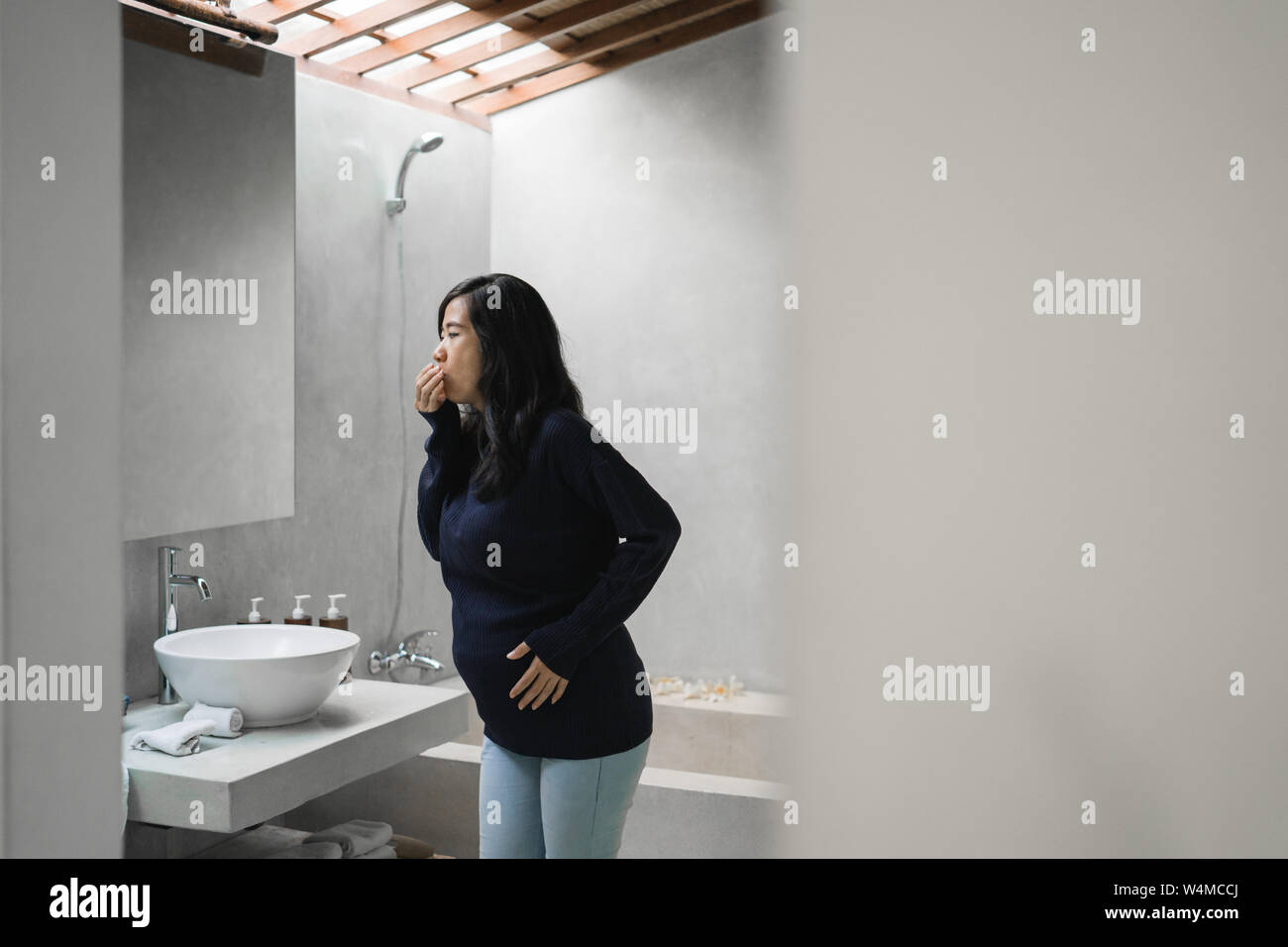 pregnant woman feels nauseous in the bathroom Stock Photo