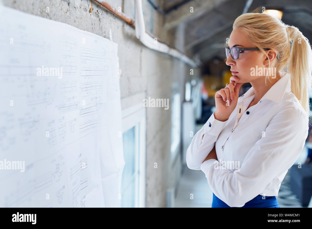 Thoughtful female architect looking on blueprint Stock Photo
