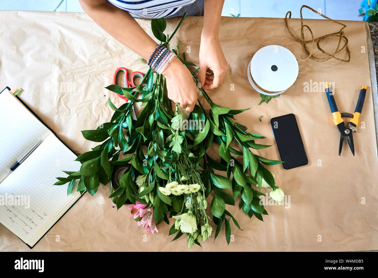 Florist selecting flowers for bouquet and arranging them together at the counter top Stock Photo