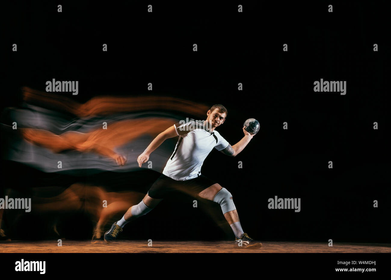Caucasian young handball player in action and motion in mixed lights ...