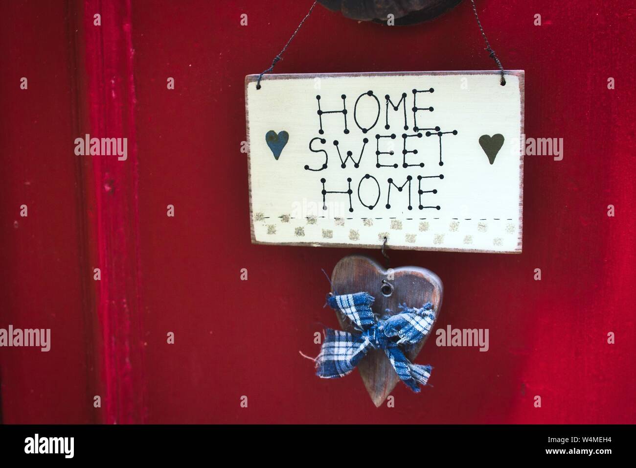 A cute Home Sweet Home sign hanging on a bright red door Stock Photo