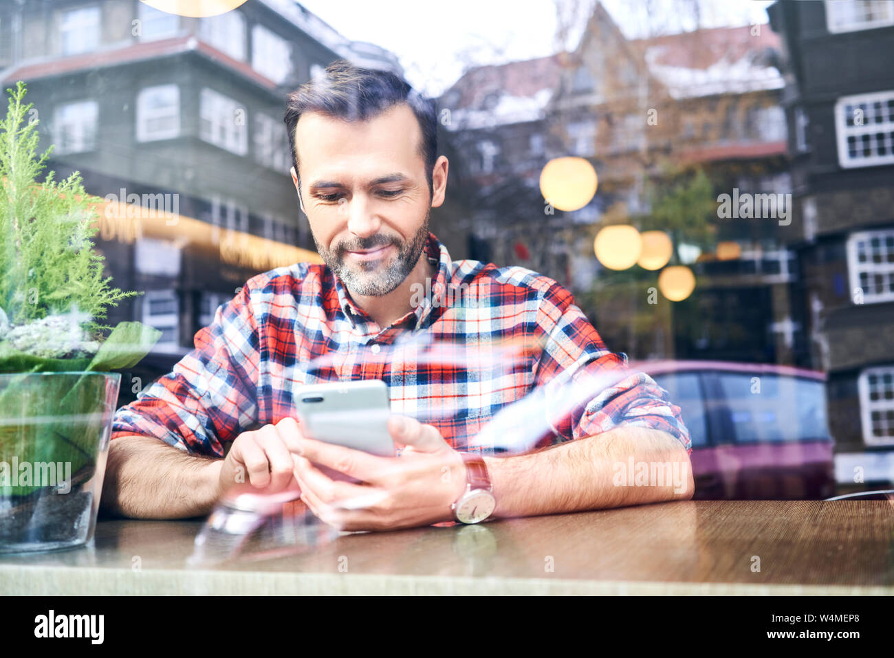 Man using smartphone while sitting in cafe during winter time Stock Photo