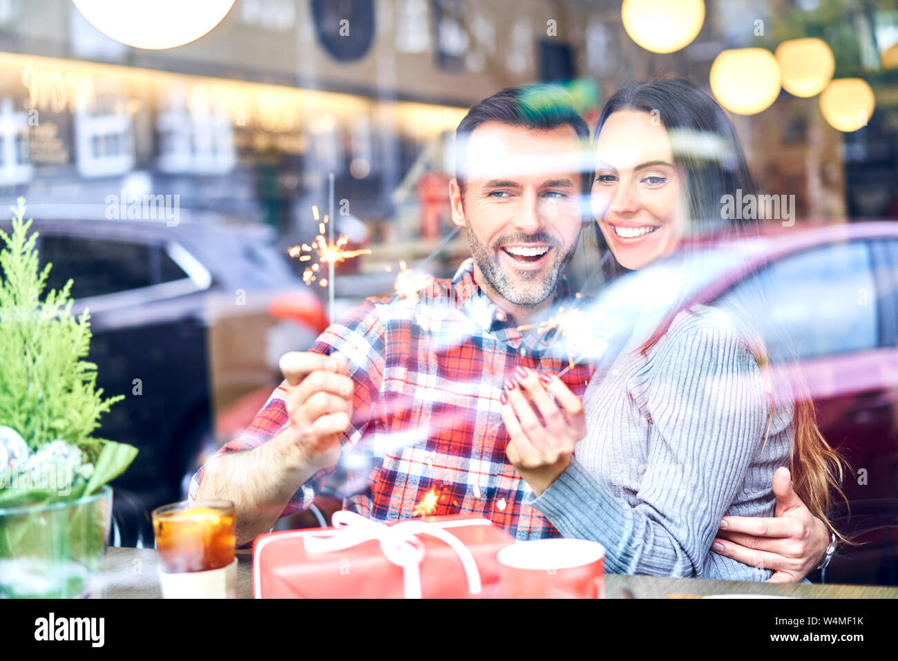 Couple sitting in cafe during Christmas and playing with sparklers Stock Photo