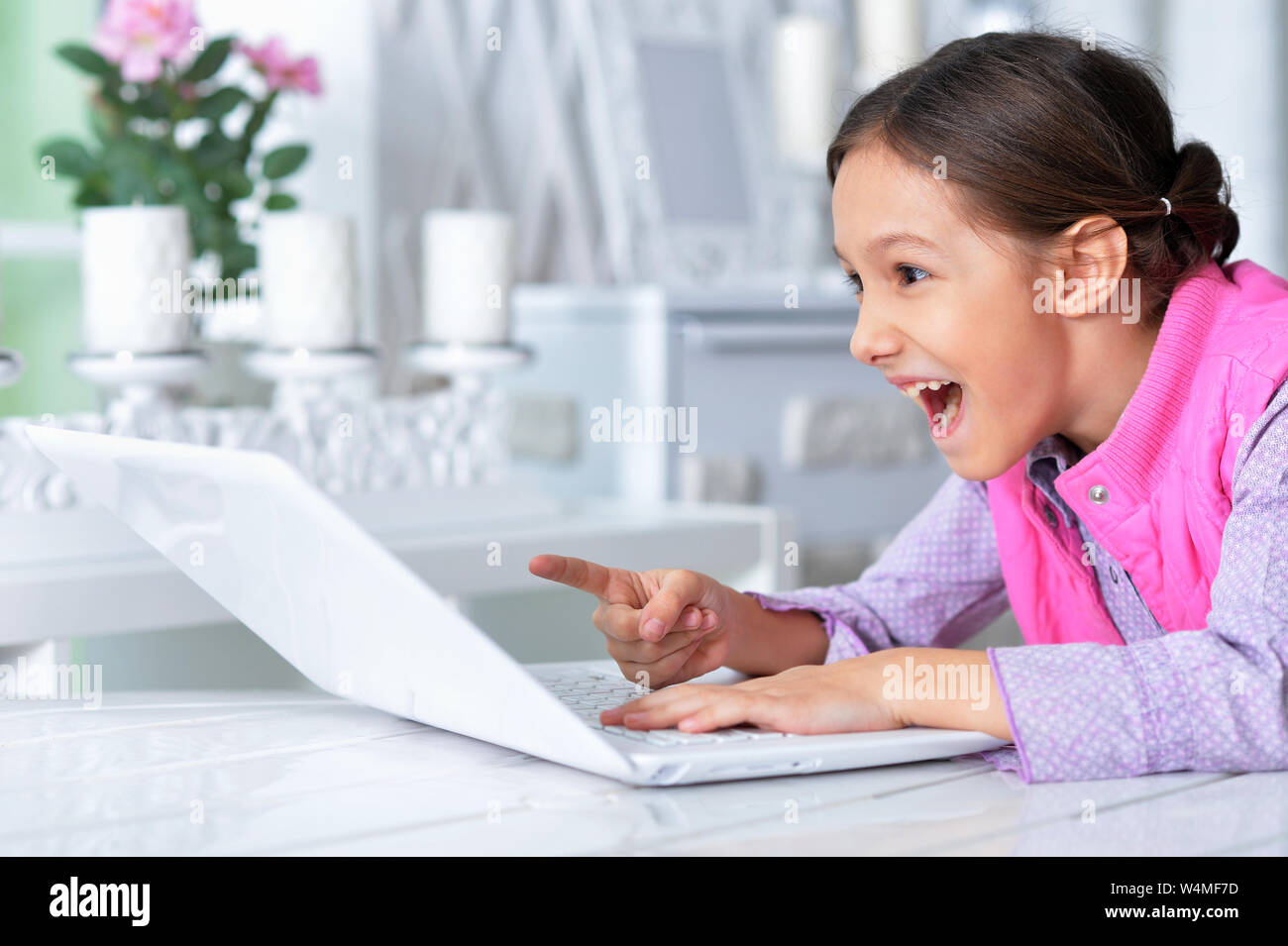 Emotional cute girl using laptop and posing at home Stock Photo - Alamy