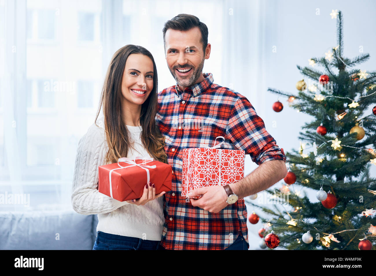 Joyful couple with christmas presents in decorated living room. Portrait of happy family Stock Photo